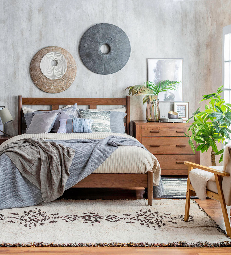 dormitorio estilo nórdico, con cama de madera y mantas en tonos neutros y azules.
