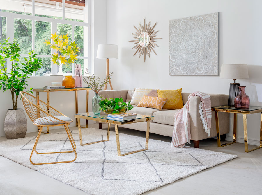 Living con alfombra beige, sofa beige y mesa y silla doradas