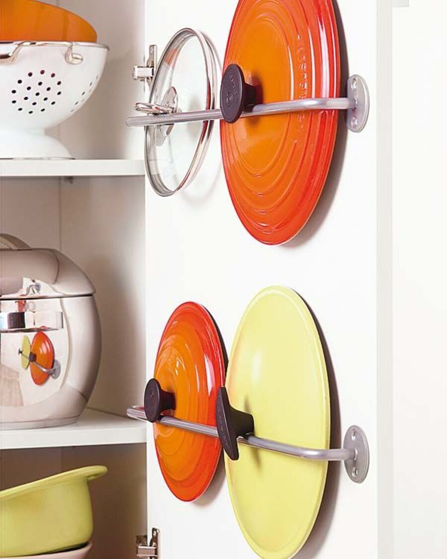 Una barra puesta en el interior de la puerta de un mueble de cocina, se vuelve el colgador ideal para organizar tapas de ollas.