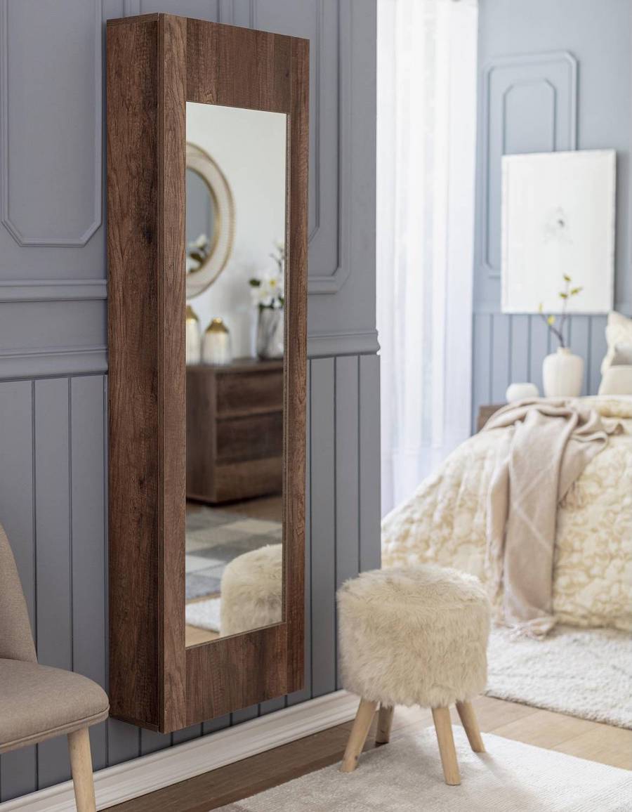 Dormitorio de estilo clásico con paredes grises con molduras, piso de madera y alfombras blancas. En uno de los muros está instalado un mueble zapatero angosto de madera oscura y espejo en su puerta. 